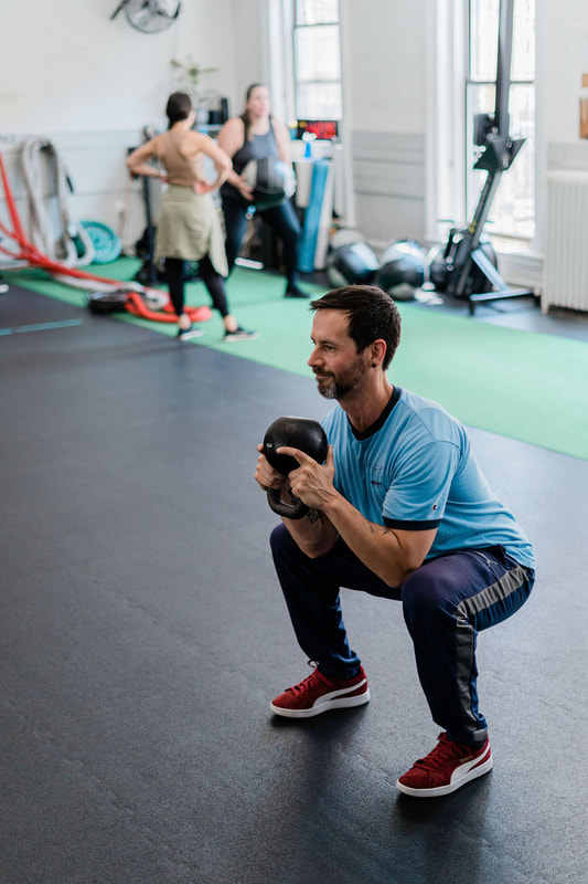 Man performing kettlebell squats during functional training in Evanston